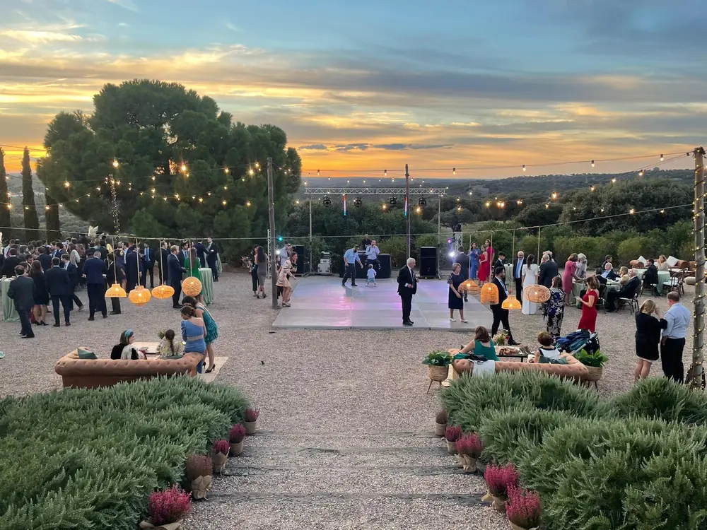 Celebración de boda al aire libre al atardecer con pista de baile y guirnaldas de luces