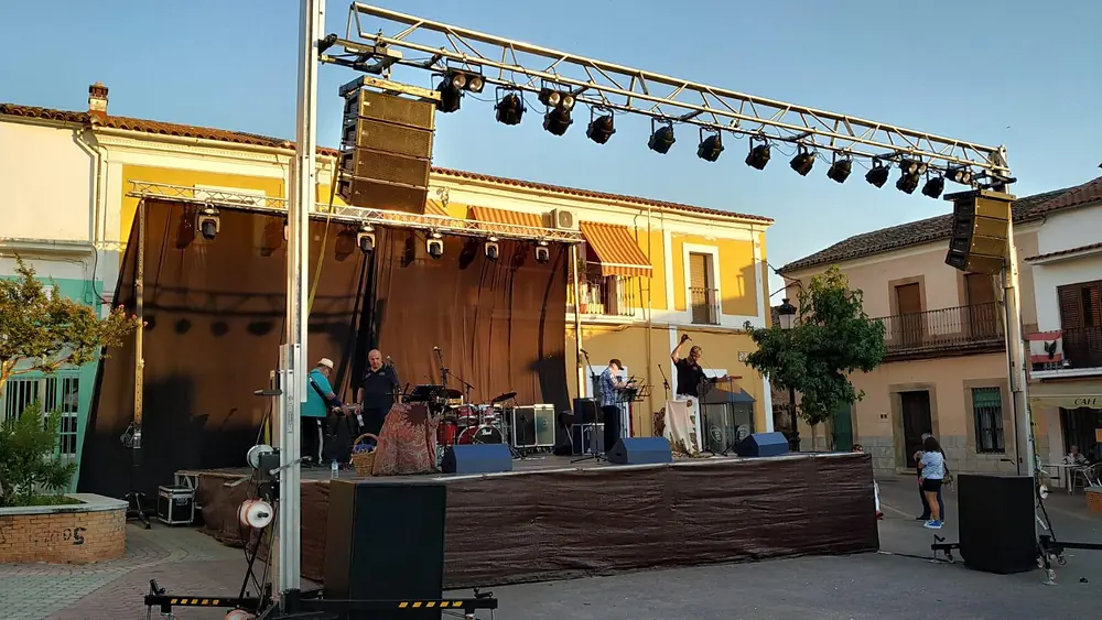 Escenario con sonido line-array y truss de iluminación en una plaza al atardecer
