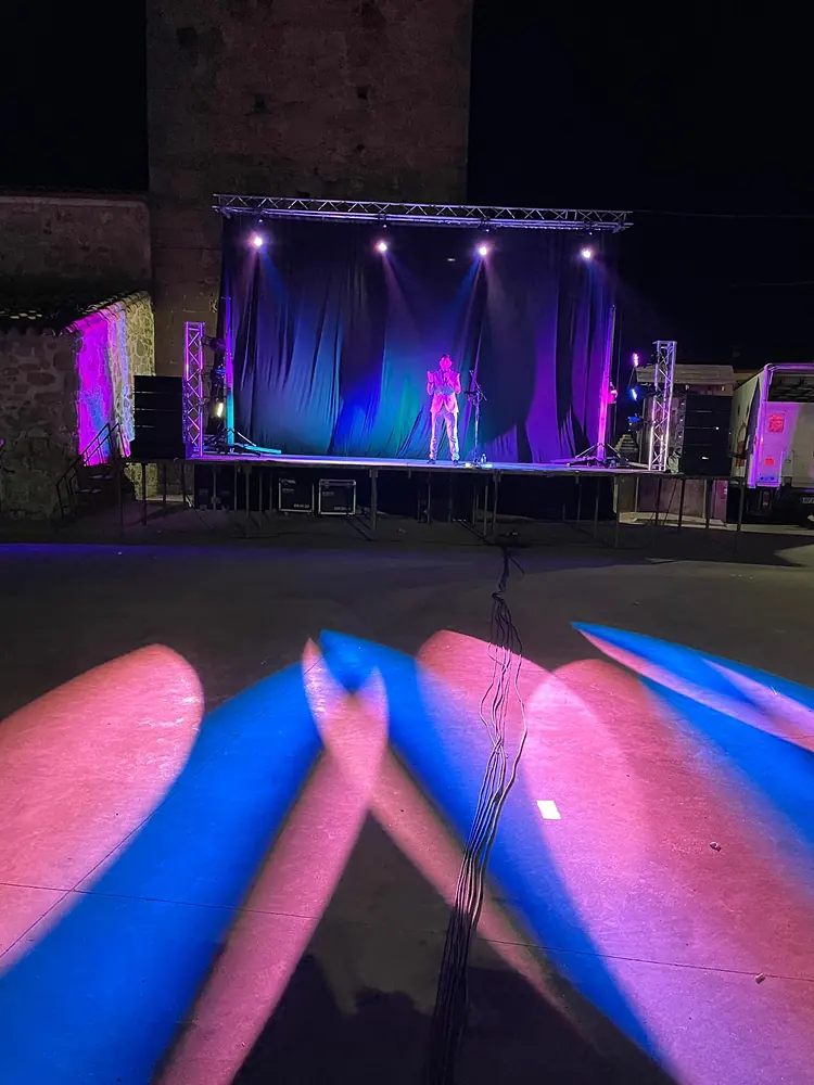 Escenario nocturno con telón azul y haces de luz rosa y azul sobre el suelo