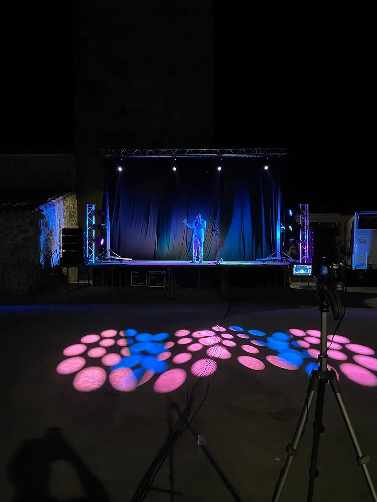 Escenario nocturno en una plaza con efectos de luz proyectados en el suelo