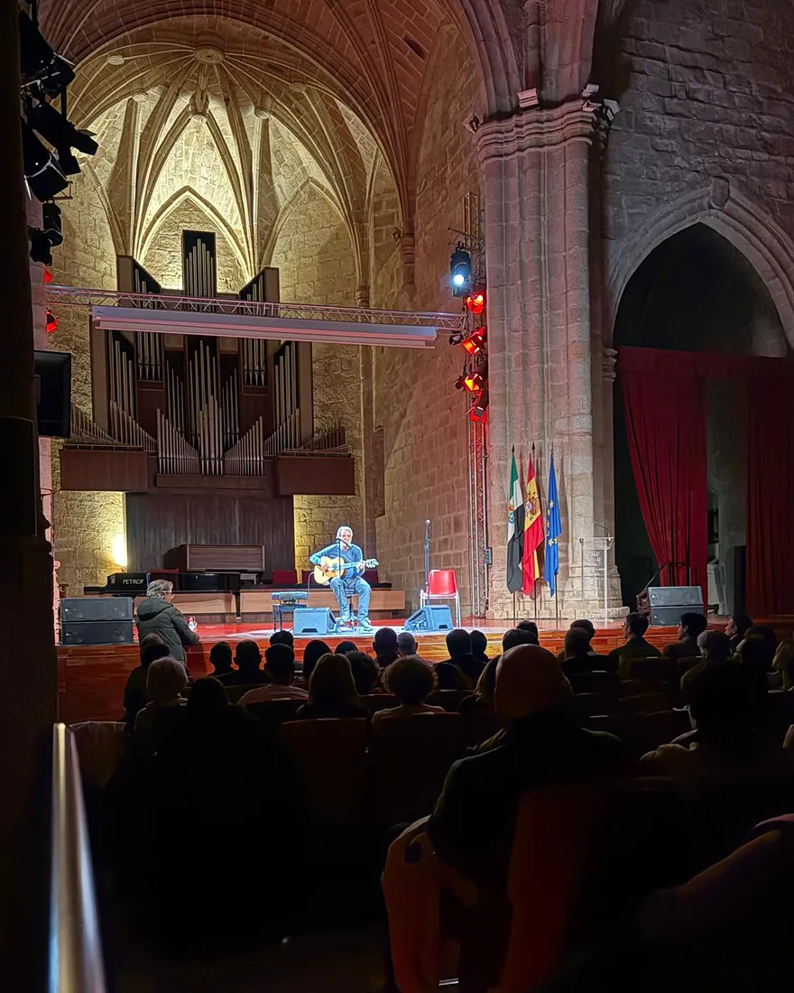 Concierto acústico de guitarra en un auditorio con bóveda gótica y órgano
