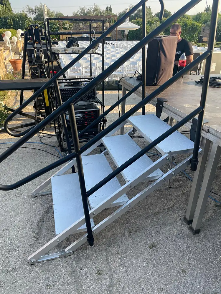 Escalera con barandilla de acceso a escenario de tarimas durante el montaje