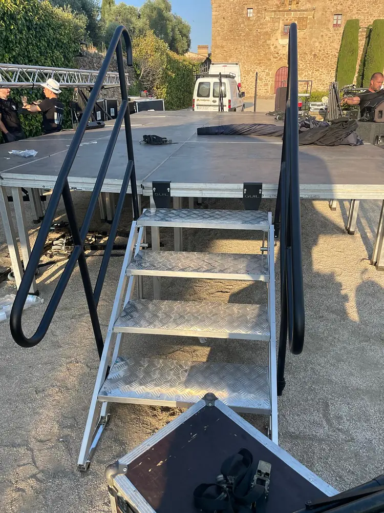 Escenario de tarimas con escalera de acceso y estructura de truss al aire libre