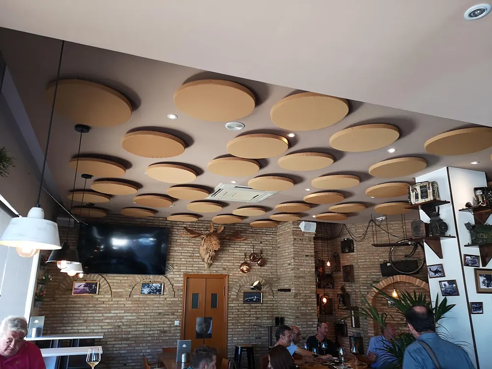 Restaurante con paneles acústicos circulares suspendidos del techo